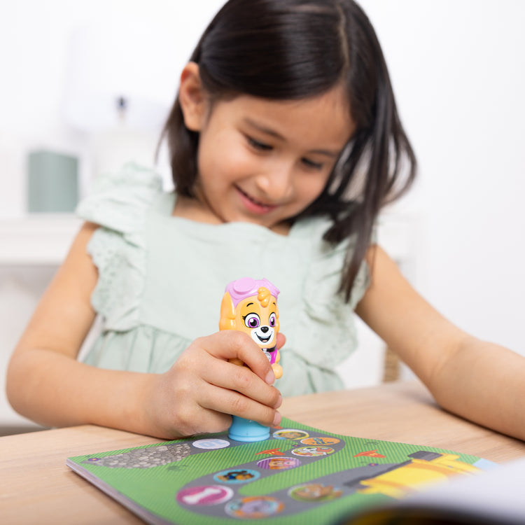 A kid playing with The Melissa & Doug Sticker WOW!™ PAW Patrol Skye Bundle: 24-Page Activity Pad, Sticker Stamper, 500 Stickers, Mini Pad, Arts and Crafts Fidget Toy Collectible Character