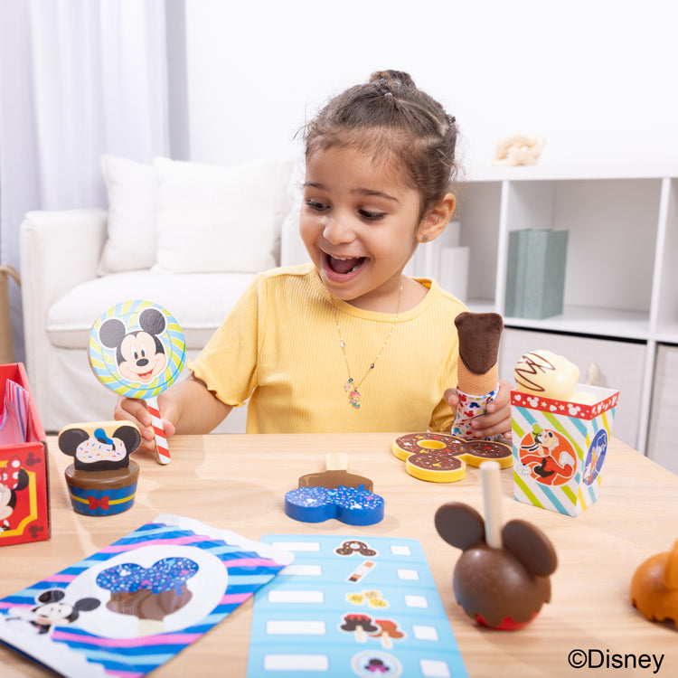 A kid playing with The Melissa & Doug Disney Snacks & Popcorn Wooden Play Food Set – 24 Pieces | Mickey Mouse, Minnie, Wooden Toy for Boys and for Girls 3+