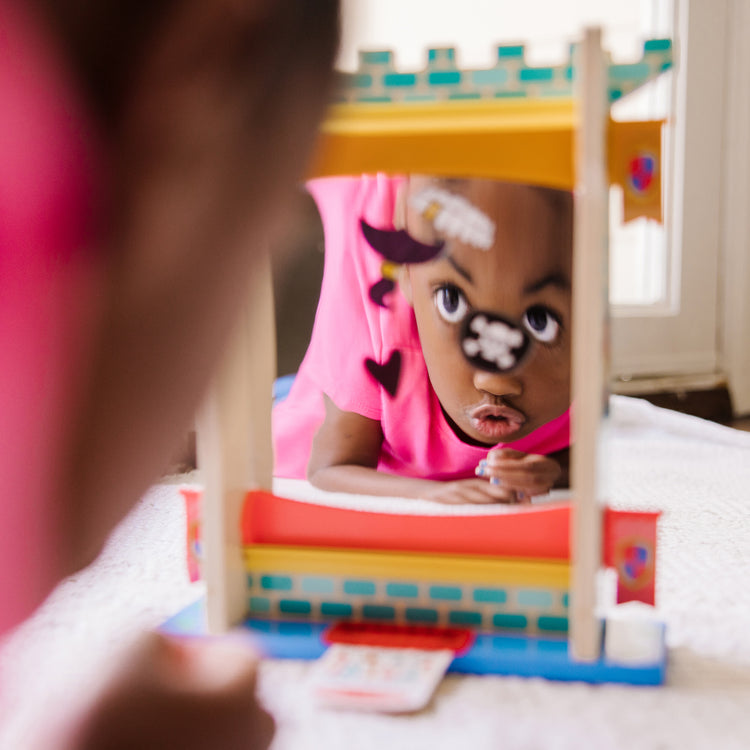 A kid playing with The Melissa & Doug Fun at the Fair! Wooden Double-Sided Funhouse Mirror