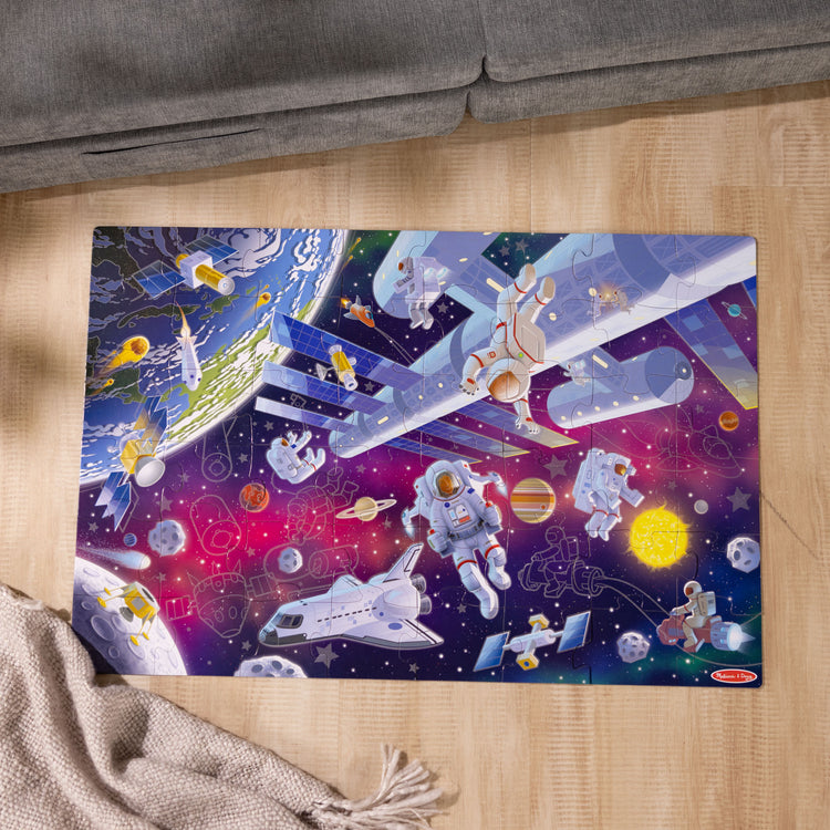 A kid playing with The Melissa & Doug Outer Space Glow-in-the-Dark Cardboard Jigsaw Floor Puzzle – 48 Pieces, for Boys and Girls 3+