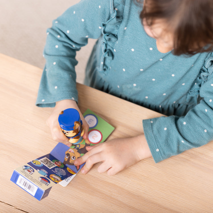 A kid playing with The Melissa & Doug Sticker WOW!™ Mini Activity Pad and 200+ Refill Stickers for Sticker Stamper Arts and Crafts Fidget Toy Collectibles – PAW Patrol Stickers