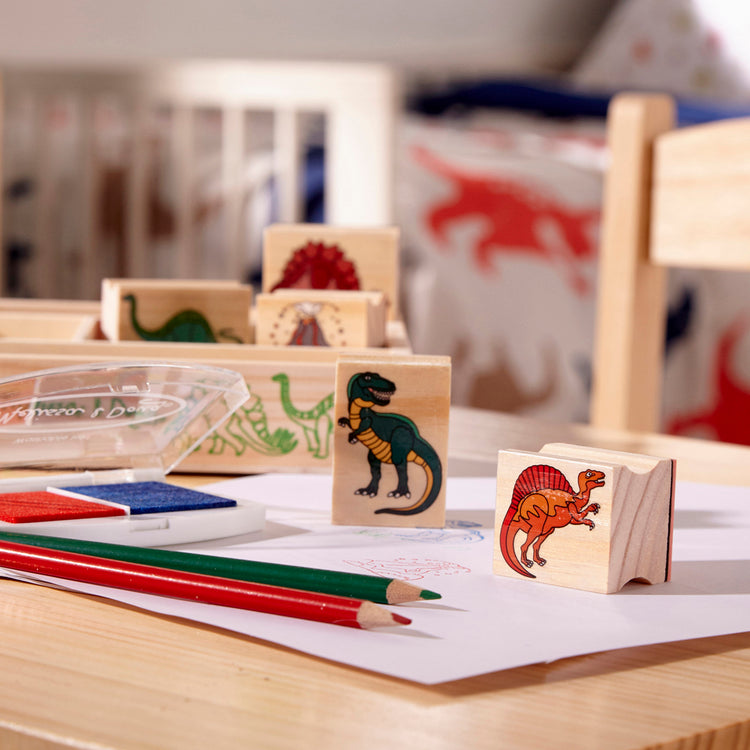 A playroom scene with The Melissa & Doug Wooden Stamp Set: Dinosaurs - 8 Stamps, 5 Colored Pencils, 2-Color Stamp Pad