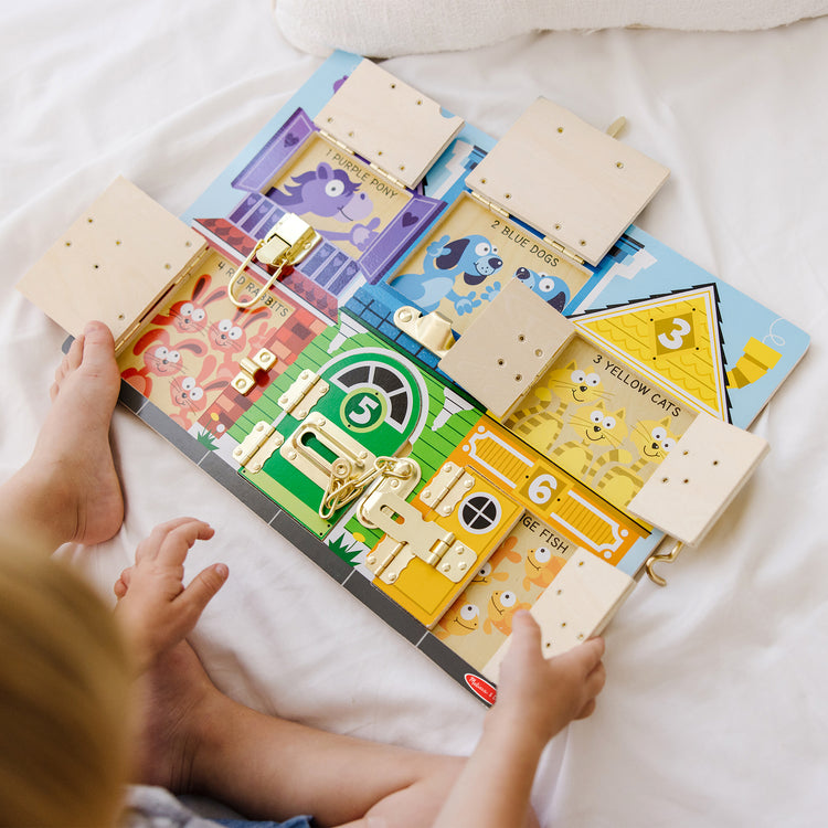 A kid playing with The Melissa & Doug Latches Wooden Activity Board