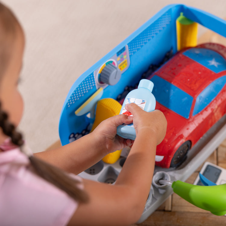 A kid playing with The Melissa & Doug Spray & Shine Car Wash Color-Changing Water Toy Play Set Boys and Girls 3+