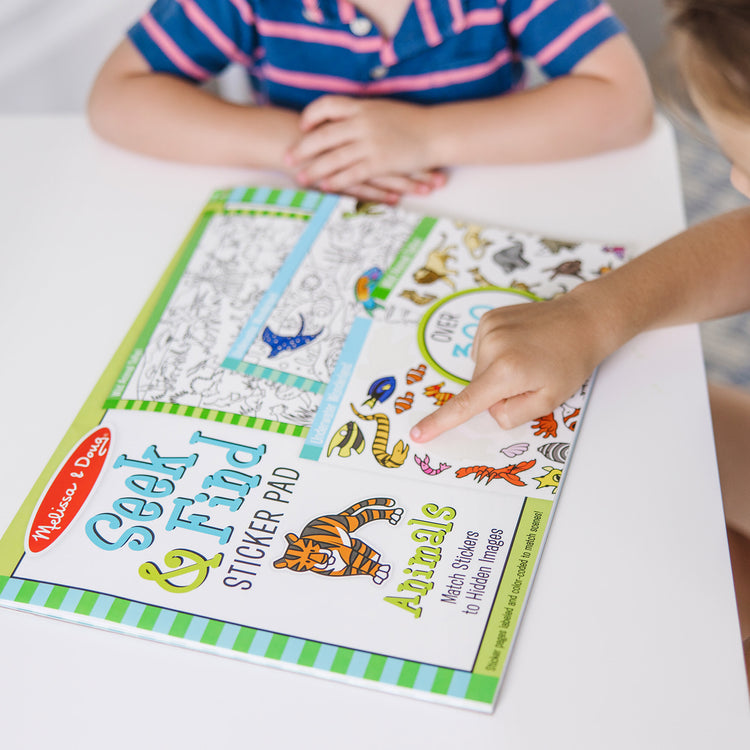 A kid playing with The Melissa & Doug Seek and Find Sticker Pad, Animals (400+ Stickers, 14 Scenes to Color)