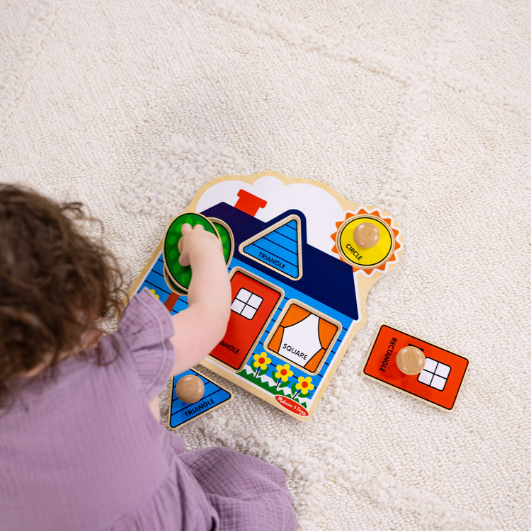 A kid playing with The Melissa & Doug First Shapes Jumbo Knob Wooden Puzzle