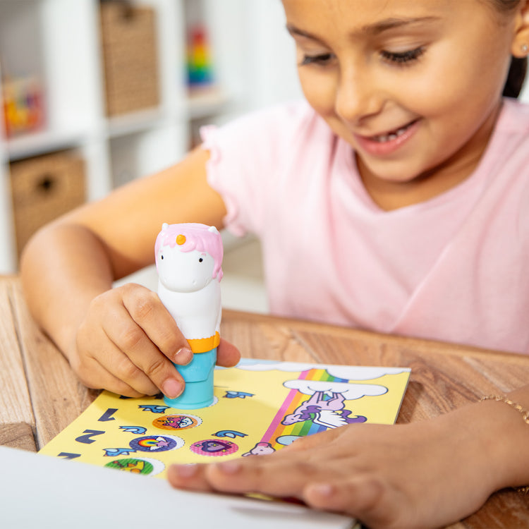 A kid playing with The Melissa & Doug Sticker WOW!™ Dog and Unicorn Bundle: 2 24-Page Activity Pads, 2 Sticker Stampers, 600 Stickers, Arts and Crafts Fidget Toy Collectible Characters