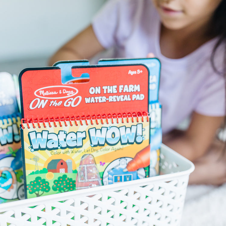 A kid playing with The Melissa & Doug On the Go Water Wow! Reusable Color with Water Activity Pad 3-Pack, Jungle, Safari, Farm