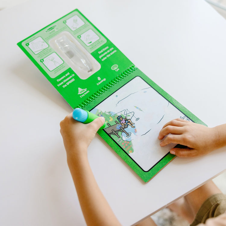 A kid playing with The Melissa & Doug Let’s Explore Water Wow! Seasons Water-Reveal Pad – Reusable On the Go Travel Activity