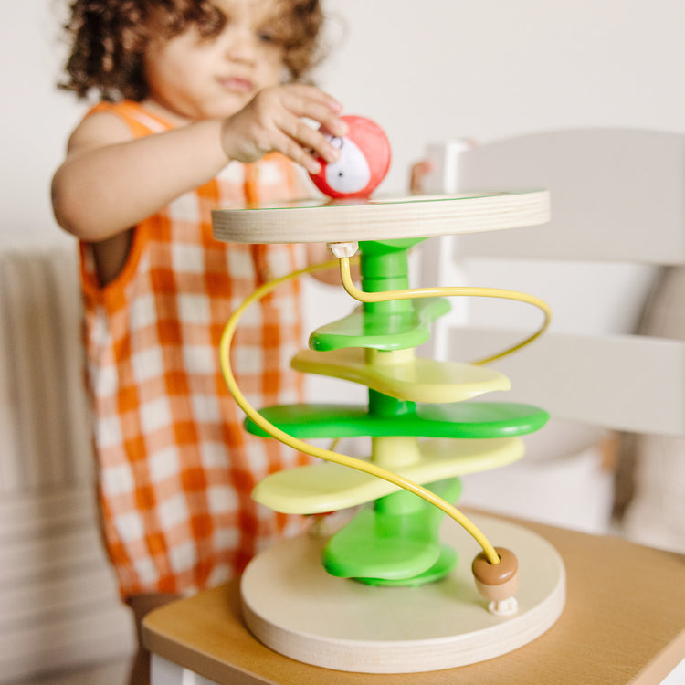 A kid playing with The Melissa & Doug Rollables Treehouse Twirl Infant and Toddler Toy (3 Pieces)