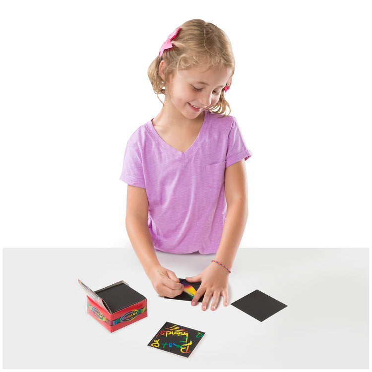 A child on white background with The Melissa & Doug Scratch Art Rainbow Mini Notes (125) With Wooden Stylus
