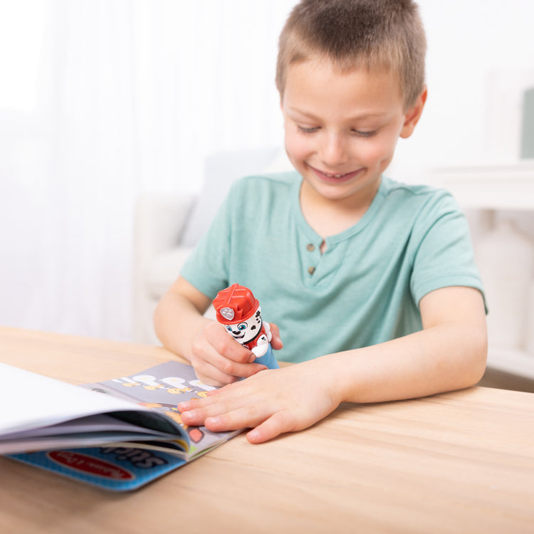 A kid playing with The Melissa & Doug Sticker WOW!™ PAW Patrol Marshall Bundle: 24-Page Activity Pad, Sticker Stamper, 500 Stickers, Mini Pad, Arts and Crafts Fidget Toy Collectible Character