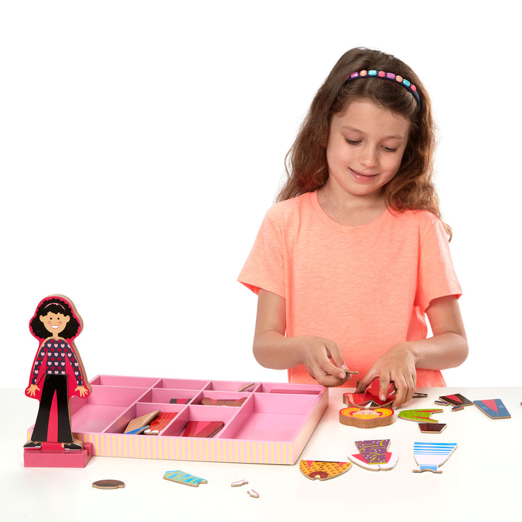 A child on white background with The Melissa & Doug Abby and Emma Deluxe Magnetic Wooden Dress-Up Dolls Play Set (55+ pcs)
