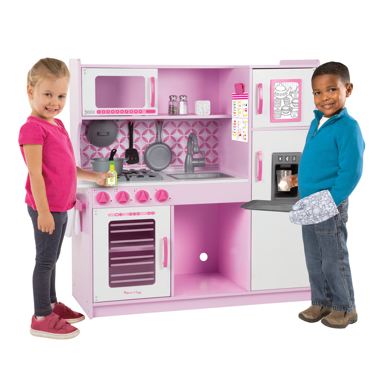 A child on white background with The Melissa & Doug Wooden Chef’s Pretend Play Toy Kitchen With “Ice” Cube Dispenser – Cupcake Pink/White