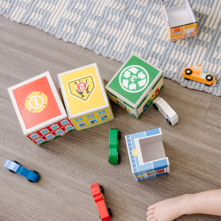 A kid playing with The Melissa & Doug Nesting and Sorting Blocks - 6 Buildings, 6 Wooden Vehicles