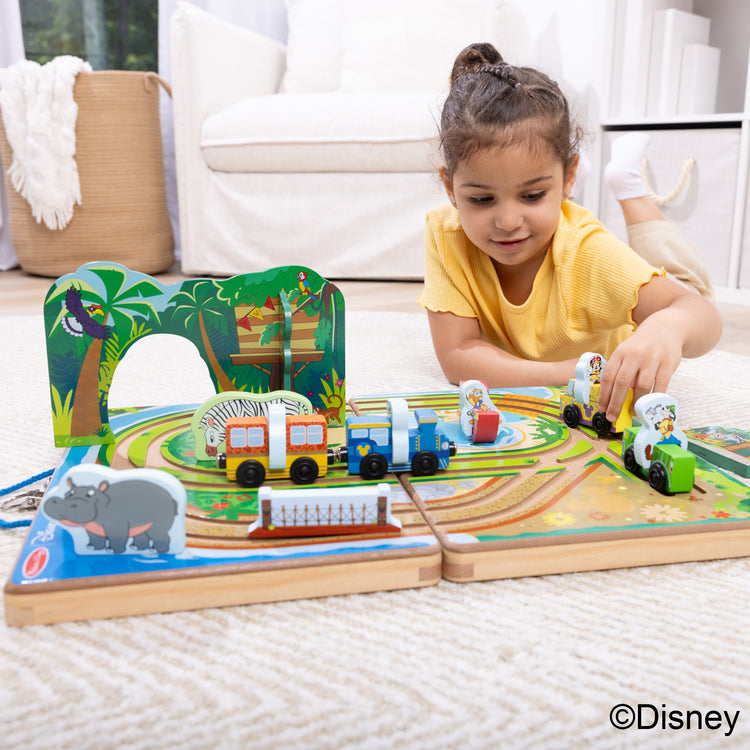 A kid playing with The Melissa & Doug Disney Take-Along Safari Adventure Wooden Play Set with Built-In Tracks – 20 Pieces | Mickey Mouse, Minnie, Wooden Toy for Boys and for Girls 3+