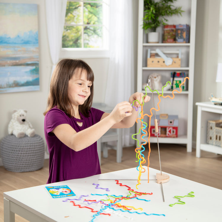 A kid playing with The Melissa & Doug Suspend Junior Family Game (31 pcs)