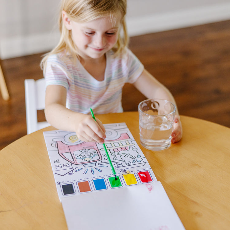 A kid playing with The Melissa & Doug Paint With Water - Vehicles, 20 Perforated Pages With Spillproof Palettes