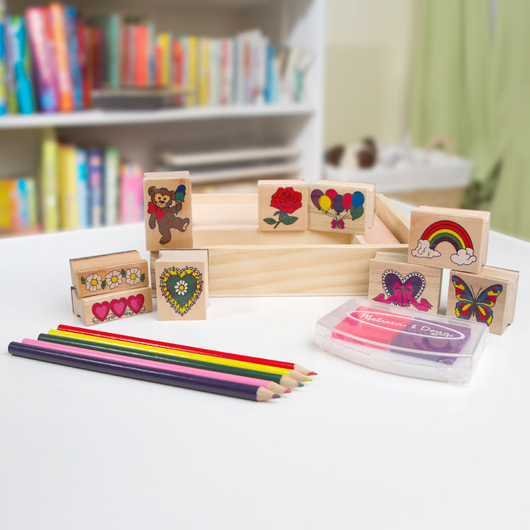 A playroom scene with The Melissa & Doug Wooden Stamp Set: Friendship - 9 Stamps, 5 Colored Pencils, and 2-Color Stamp Pad