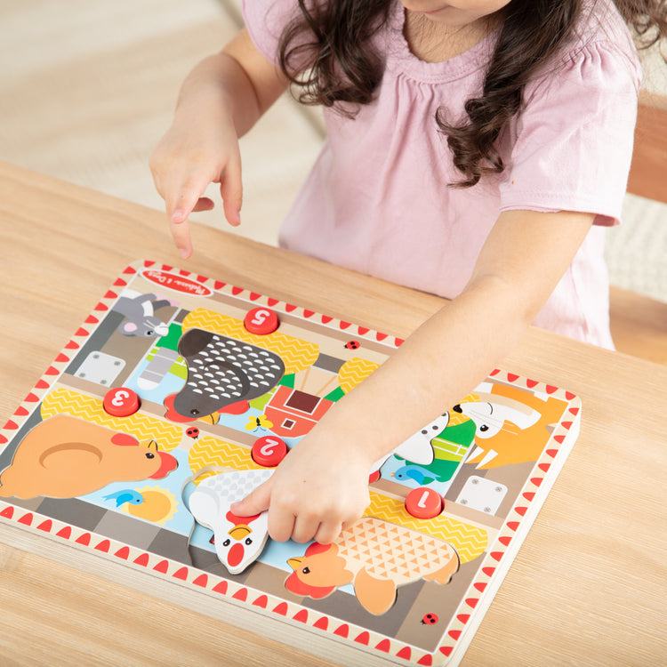 A kid playing with The Happy Hens Push to Pop Puzzle