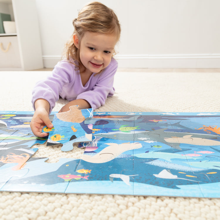 A kid playing with The Melissa & Doug Beneath the Waves, Ocean-Themed Search and Find Jumbo Floor Puzzle, 48-Piece Jigsaw Puzzle with Learning Activity, Over 4 Ft Long, Kids Puzzles for Girls & Boys Ages 4 and Up