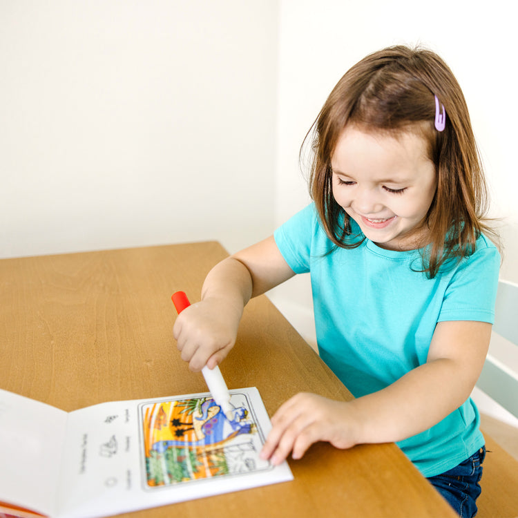 A kid playing with The Melissa & Doug On the Go ColorBlast! Travel Activity Book With No-Mess Marker - Dinosaur