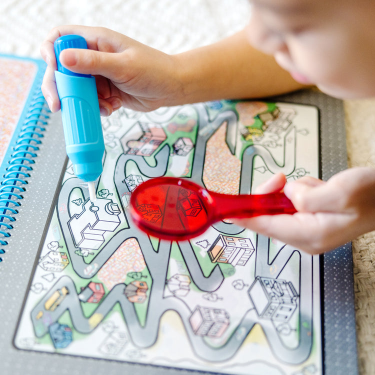 A kid playing with The Melissa & Doug On the Go Water Wow! Reusable Water-Reveal Deluxe Activity Pad – Around Town