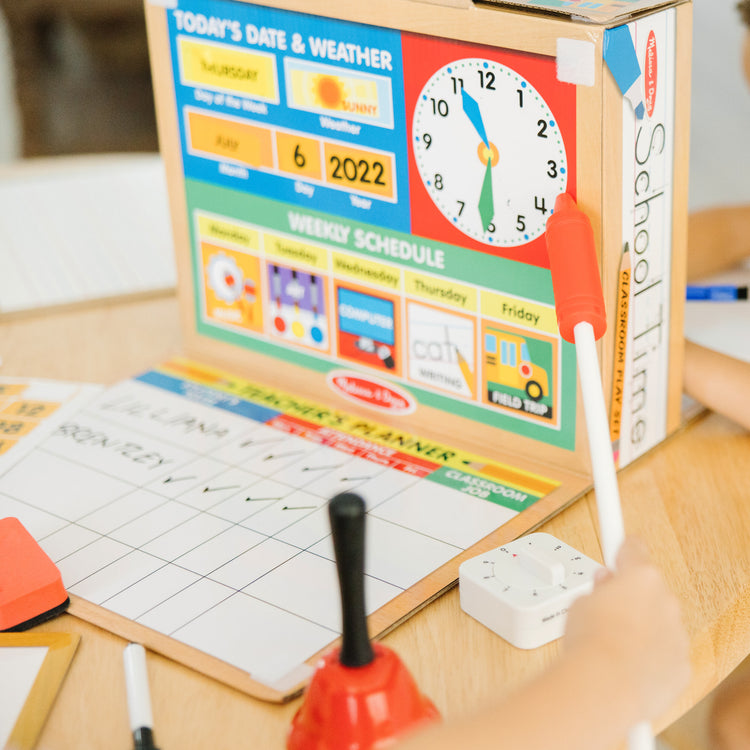 A kid playing with The Melissa & Doug School Time! Classroom Play Set Game - Be Teacher or Student