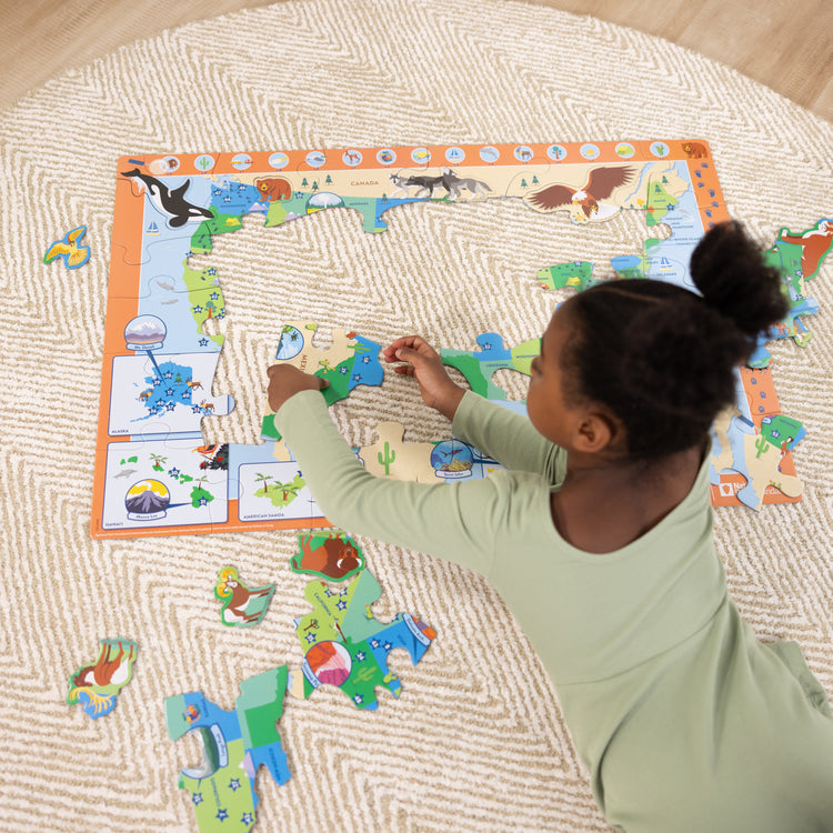 A kid playing with The Melissa & Doug National Parks U.S.A. Map Floor Puzzle – 45 Jumbo and Animal Shaped Pieces, Search-and-Find Activities, Park and Animal ID Guide
