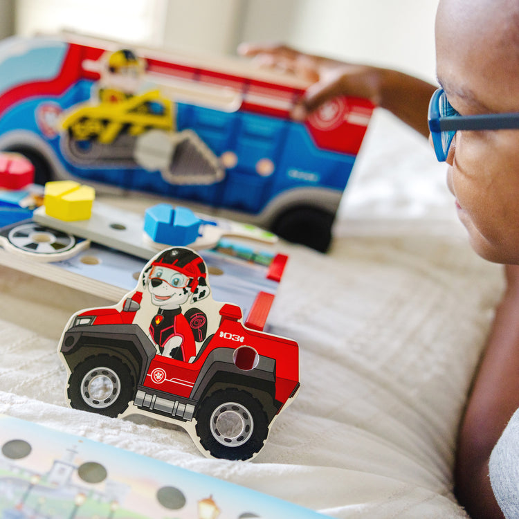 A kid playing with The Melissa & Doug PAW Patrol Match & Build Mission Cruiser