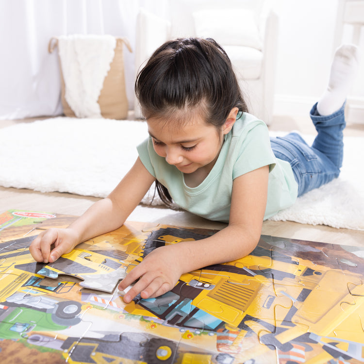 The front of the box for The Melissa & Doug Building Site, Construction Themed Jumbo Floor Puzzle, 48‑Piece Construction Vehicle Jigsaw Puzzle, 3 x 2 Foot Toddler Puzzles for Kids Ages 3+