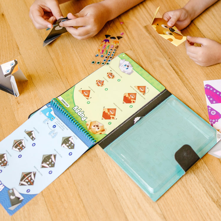 A kid playing with The Melissa & Doug On the Go Origami Animals Craft Activity Set - 38 Stickers, 40 Origami Papers