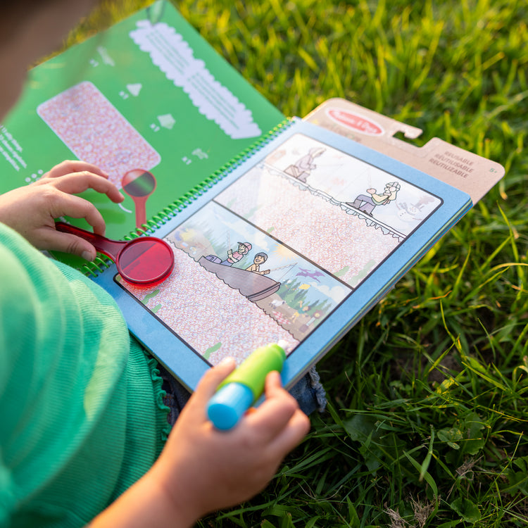 A kid playing with The Melissa & Doug Let’s Explore Water Wow! Outdoor Adventure Deluxe Water-Reveal Pad – Reusable On The Go Travel Activity