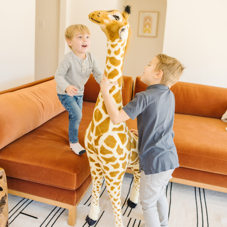 A kid playing with The Melissa & Doug Giant Giraffe - Lifelike Plush Stuffed Animal (over 4 feet tall)