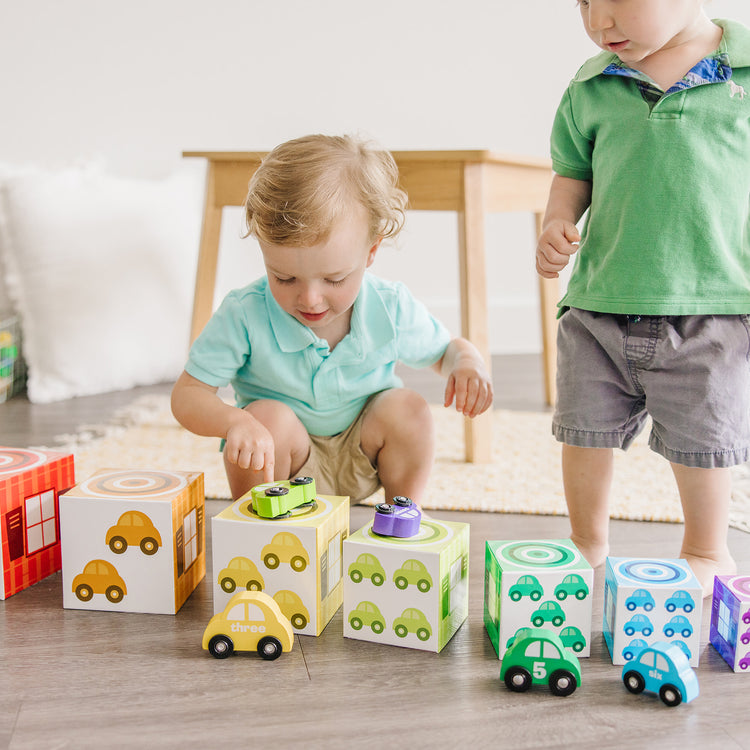 A kid playing with The Melissa & Doug Nesting and Sorting Garages and Cars With 7 Graduated Garages and 7 Stackable Wooden Cars