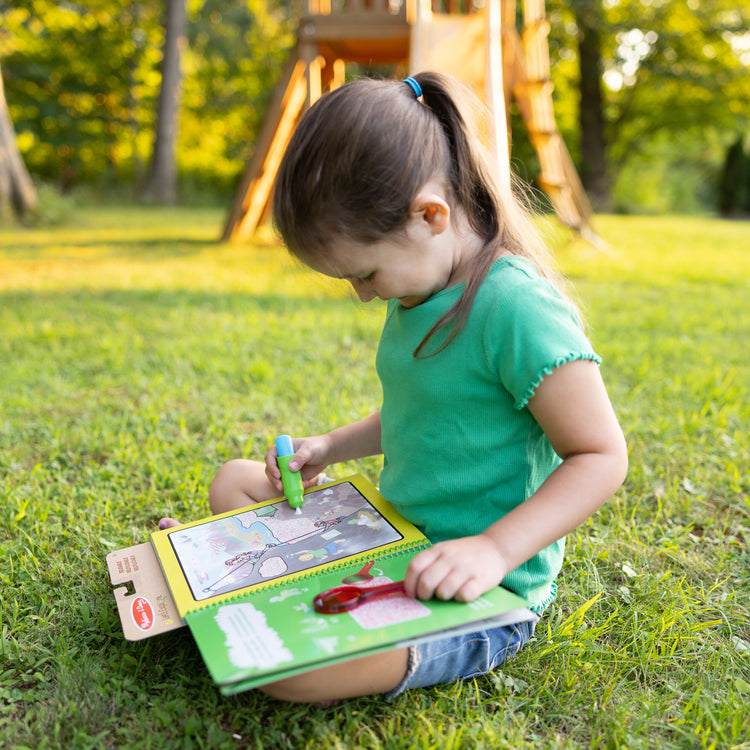 A kid playing with The Melissa & Doug Let’s Explore Water Wow! Outdoor Adventure Deluxe Water-Reveal Pad – Reusable On The Go Travel Activity