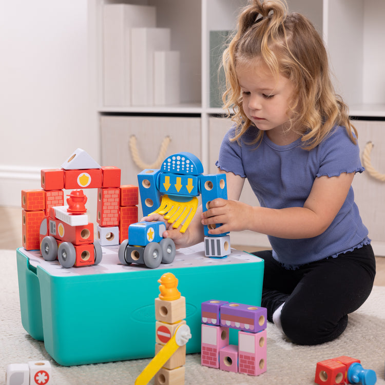 A kid playing with The Melissa & Doug Blockables™ Deluxe City Snap And Play Amazon Exclusive, Mix and Match Connectable Wooden Building Blocks Play Set With Storage Bin and Play Lid (122 Pcs)
