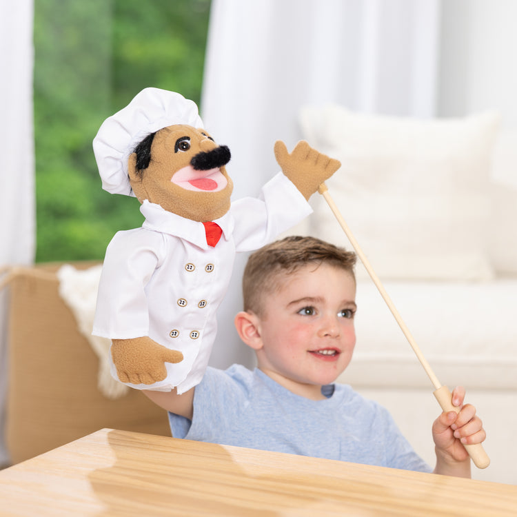 A kid playing with The Melissa & Doug Chef Puppet (Al Dente) with Detachable Wooden Rod