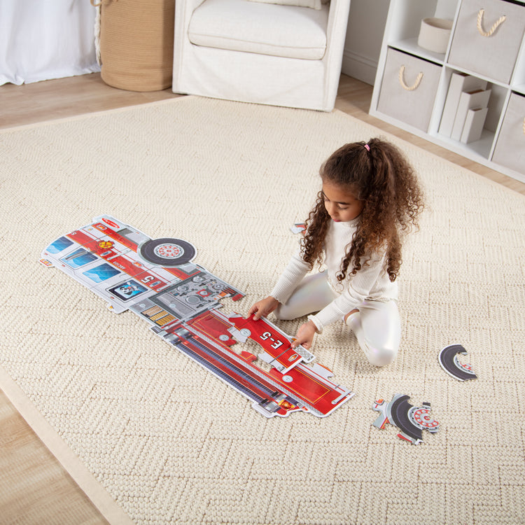 A kid playing with The Melissa & Doug Giant Fire Truck Shaped Jumbo Floor Puzzle, 24-Piece Fire Engine Jigsaw Puzzle, Over 4 Ft Long Kids Puzzles for Toddlers Ages 3+