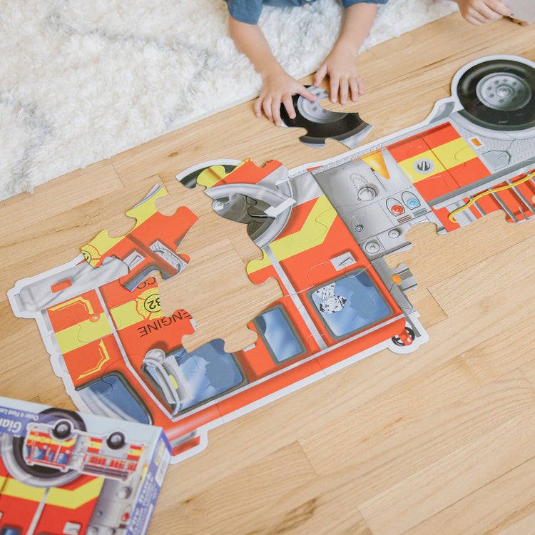 A kid playing with The Melissa & Doug Fire Truck Jumbo Jigsaw Floor Puzzle (24 pcs, 4 feet long)