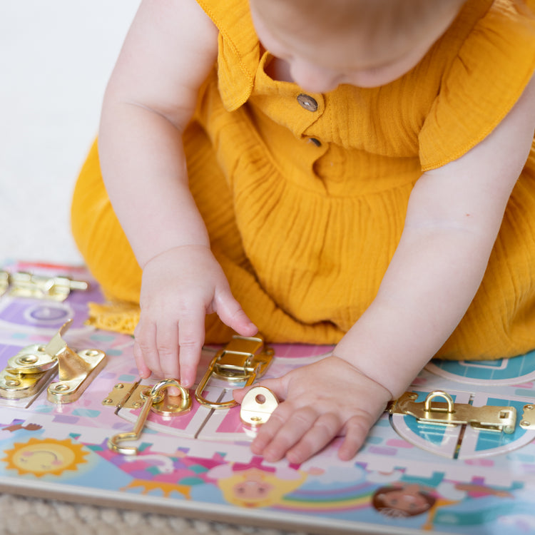 A kid playing with The Melissa & Doug Castle Latches Board with 6 Brass-Plated Doors and Locks - Wooden Sensory Toy for Ages 3+