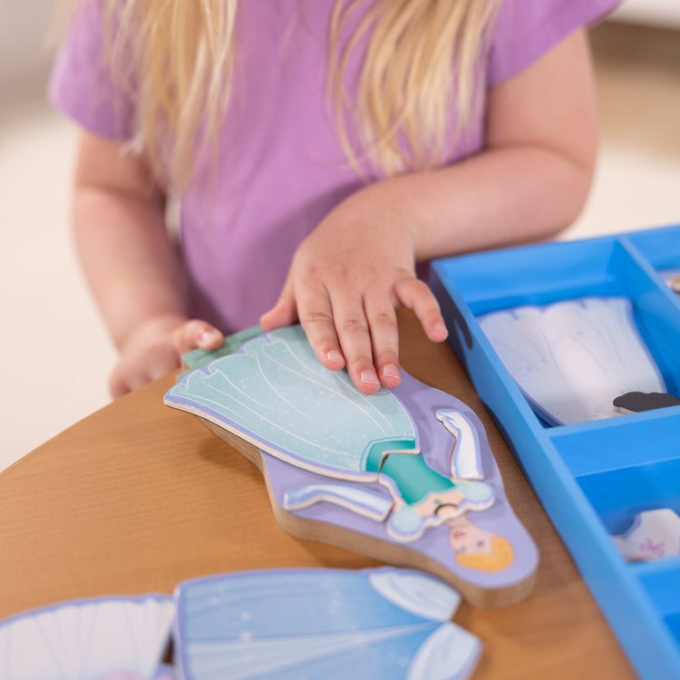 A kid playing with The Melissa & Doug Disney Princess Cinderella Magnetic Dress-Up Wooden Doll Pretend Play Set (30+ pcs)