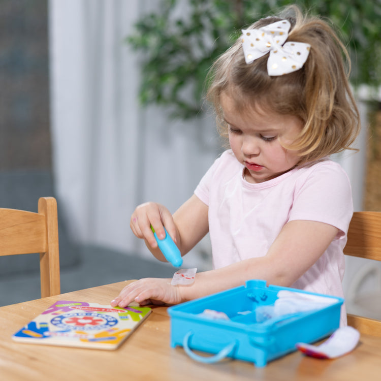 The front of the box for The Melissa & Doug Boo-Boos & Bandages Reusable First Aid Pretend Play Set for Ages 3+
