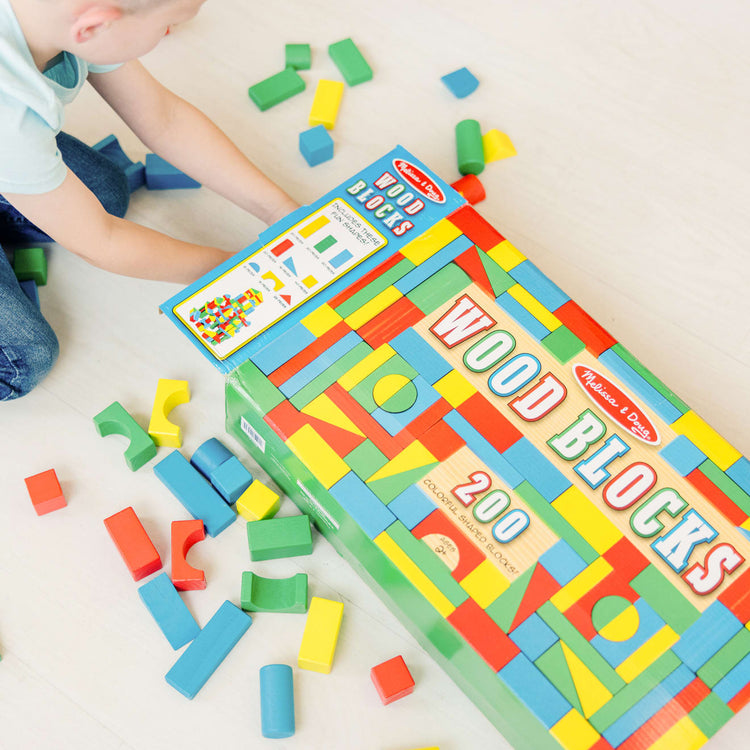 A kid playing with the Melissa & Doug Wooden Building Block Set - 200 Blocks in 4 Colors and 9 Shapes