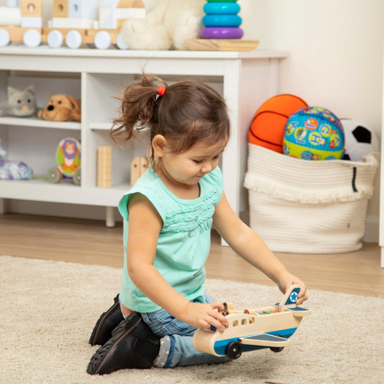 A kid playing with the Melissa & Doug Wooden Airplane Play Set With 4 Play Figures and 4 Suitcases