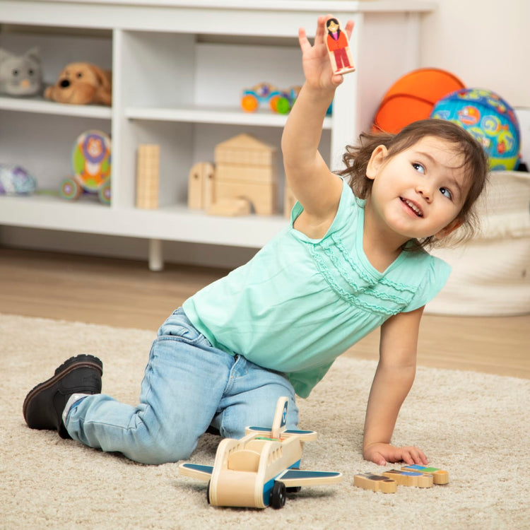 A kid playing with the Melissa & Doug Wooden Airplane Play Set With 4 Play Figures and 4 Suitcases