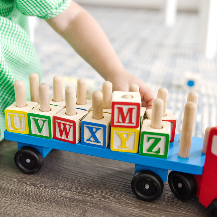 A kid playing with the Melissa & Doug Alphabet Blocks Wooden Truck Educational Toy