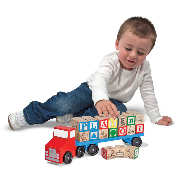 A child on white background with the Melissa & Doug Alphabet Blocks Wooden Truck Educational Toy