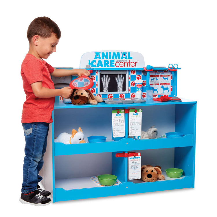 A child on white background with the Melissa & Doug Animal Care Veterinarian and Groomer Wooden Activity Center for Plush Stuffed Pets (Not Included)