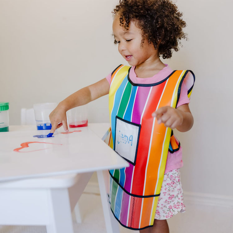 A kid playing with the Melissa & Doug Art Essentials Artist Smock - One Size Fits All